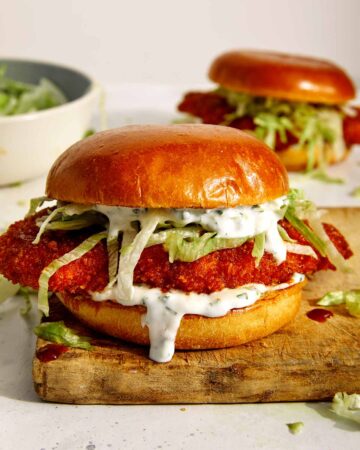 Baked hot honey chicken sandwiches on a cutting board.