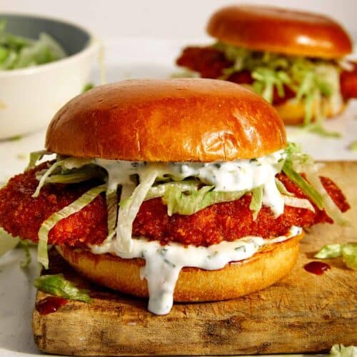 Baked hot honey chicken sandwiches on a cutting board.