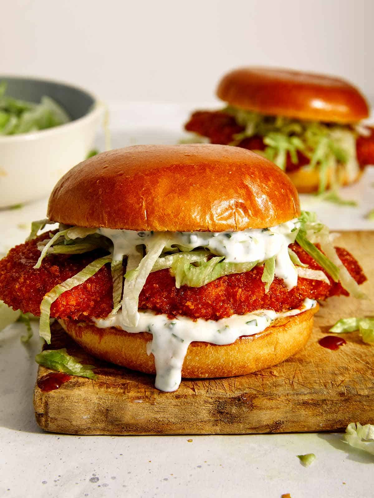 Baked hot honey chicken sandwiches on a cutting board. 