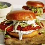 Baked hot honey chicken sandwiches on a cutting board.