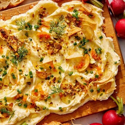 Butter board with bread and radishes on the side.