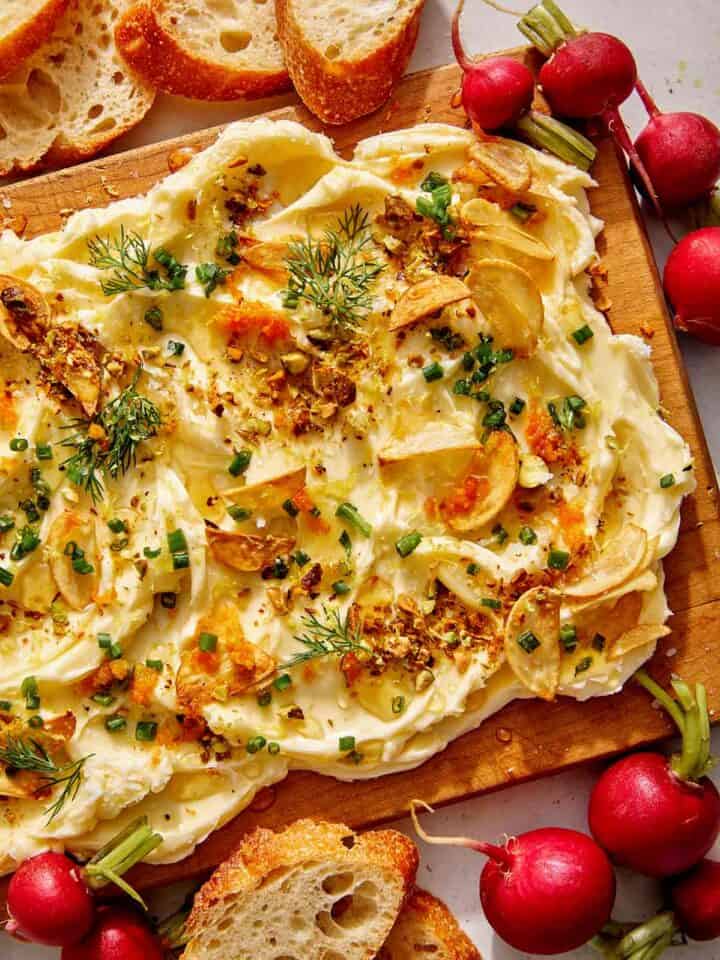 Butter board with bread and radishes on the side.