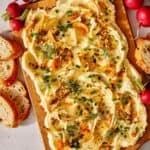 Butter board with toppings and bread and radishes on the side.