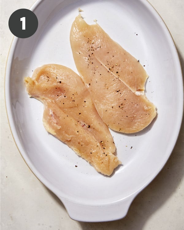 Chicken in a baking dish with salt and pepper.