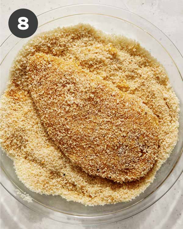 A chicken breast being coated in panko to make a chicken sandwich.