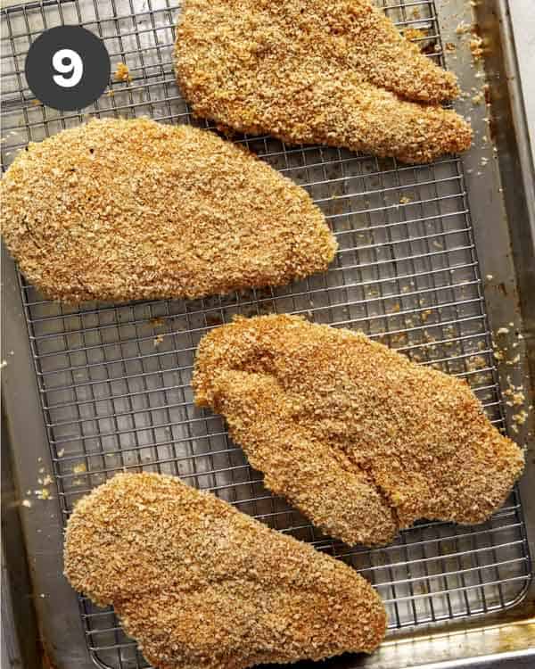 Panko coated chicken breasts on a baking sheet.