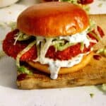 Baked hot honey chicken sandwich on a cutting board.