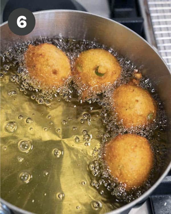 Hush Puppies finishing up frying in a pot of hot oil.