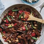 Kung pao beef in a skillet with rice on the side.