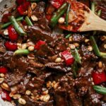 Kung pao beef in a skillet with rice on the side.