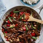 Kung pao beef in a skillet with rice on the side.