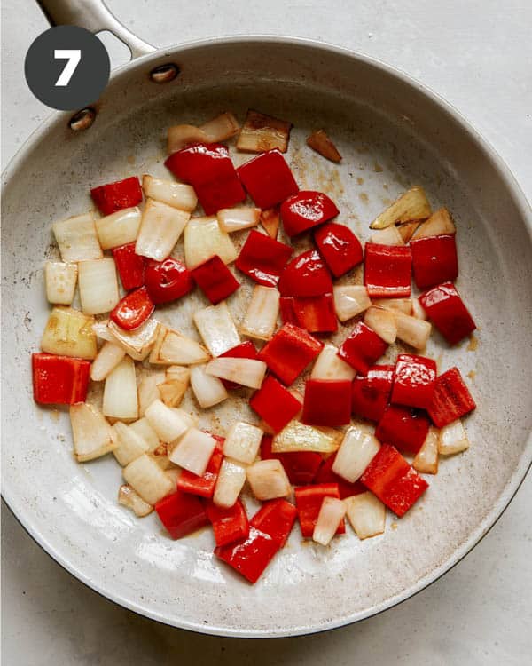 Peppers and onions cooking in a skillet. 