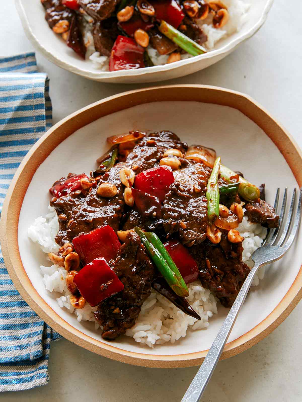 Kung pao beef in two bowls over rice. 