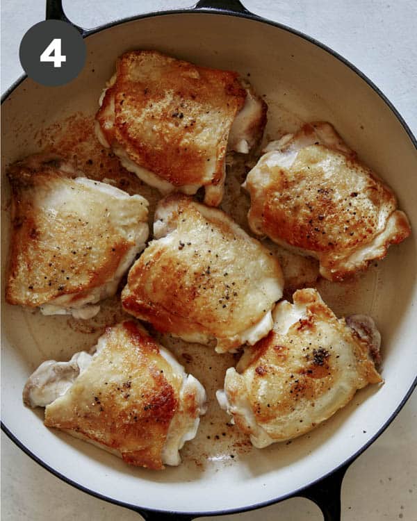 Seared and seasoned chicken thighs in a skillet.