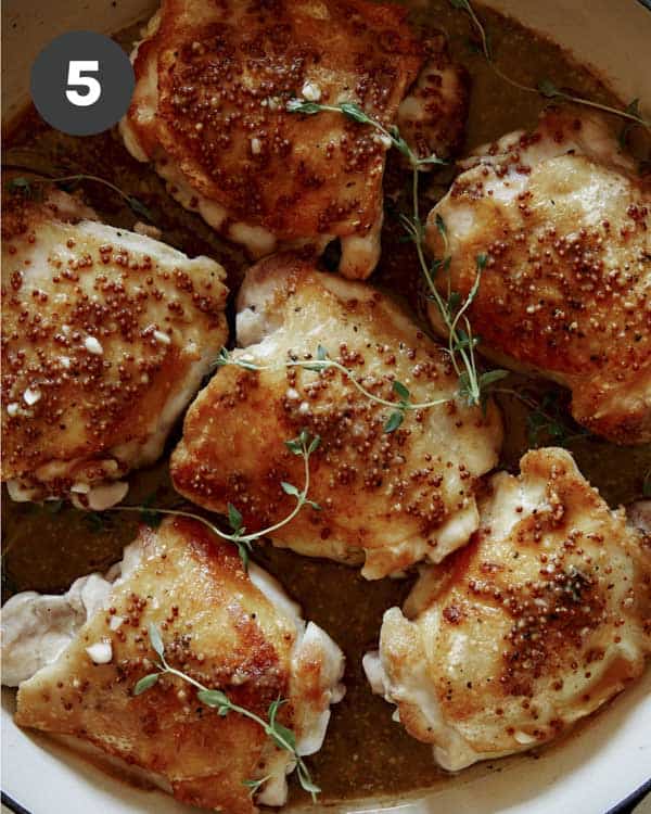 Seared chicken thighs with sauce poured over and sprigs of thyme.