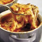 French onion soup recipe in a bowl with a spoon in it.