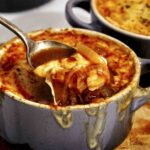 French onion soup recipe in a bowl with a spoon in it.