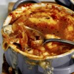 French onion soup recipe in a bowl with a spoon in it.