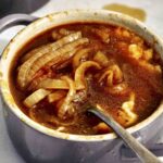 French Onion soup recipes in a bowl with a spoon in it.