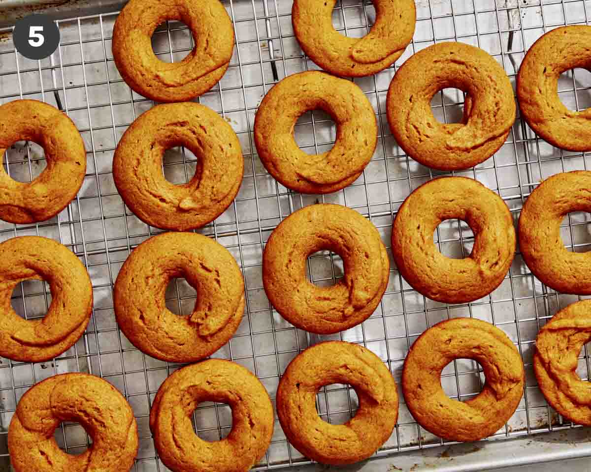 Baked pumpkin donuts being cooled on a rack.