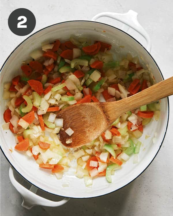 Cooking vegetables in a stock pot to make chicken noodle soup. 