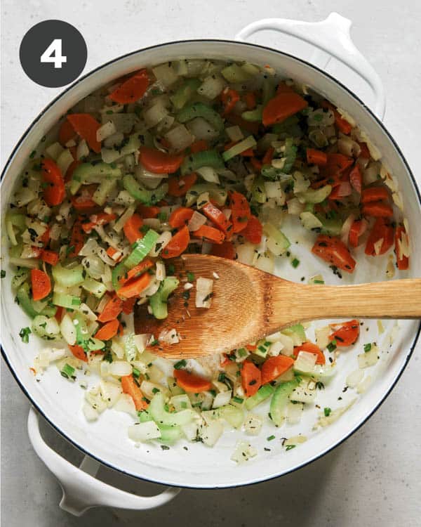Vegetables cooking in a stock pot to make chicken noodle soup.