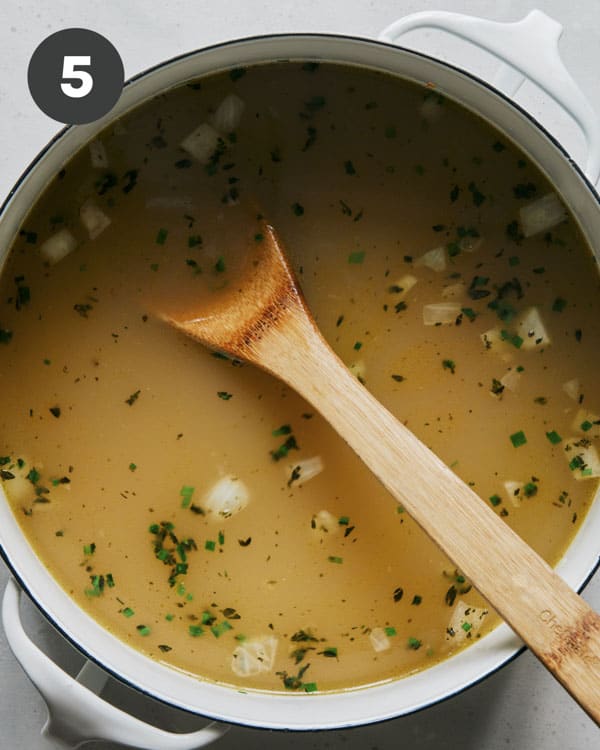 Chicken stock and vegetables in a stock pot.
