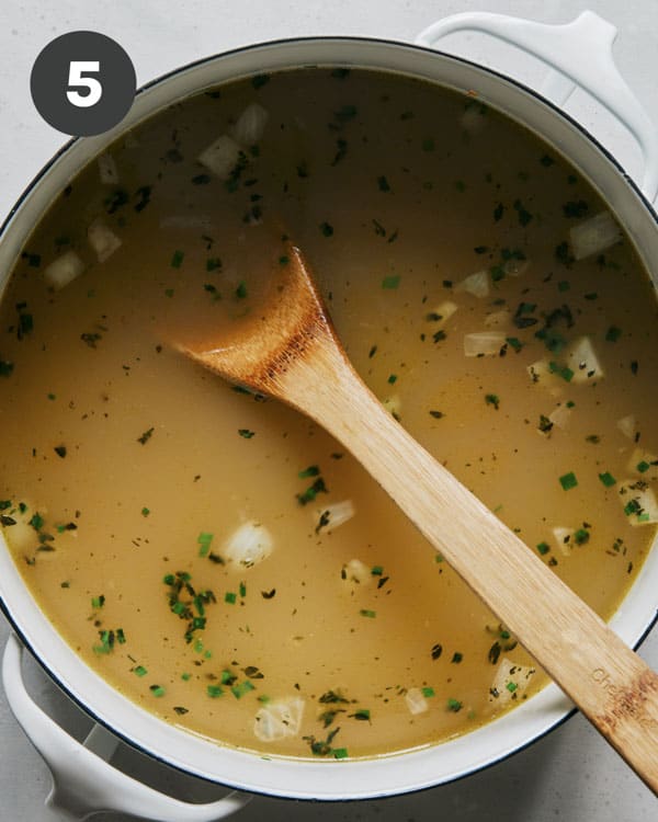 Chicken stock and vegetables in a stock pot. 