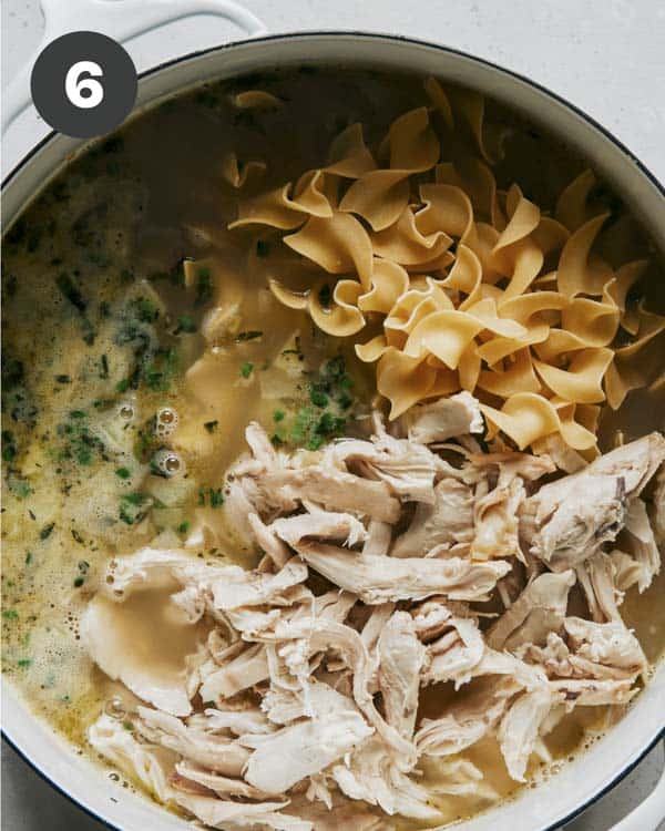 Egg noodles and chicken added to a stock pot for chicken noodle soup.