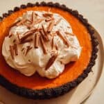 Pumpkin pie with a chocolate crust piled with whipped cream.