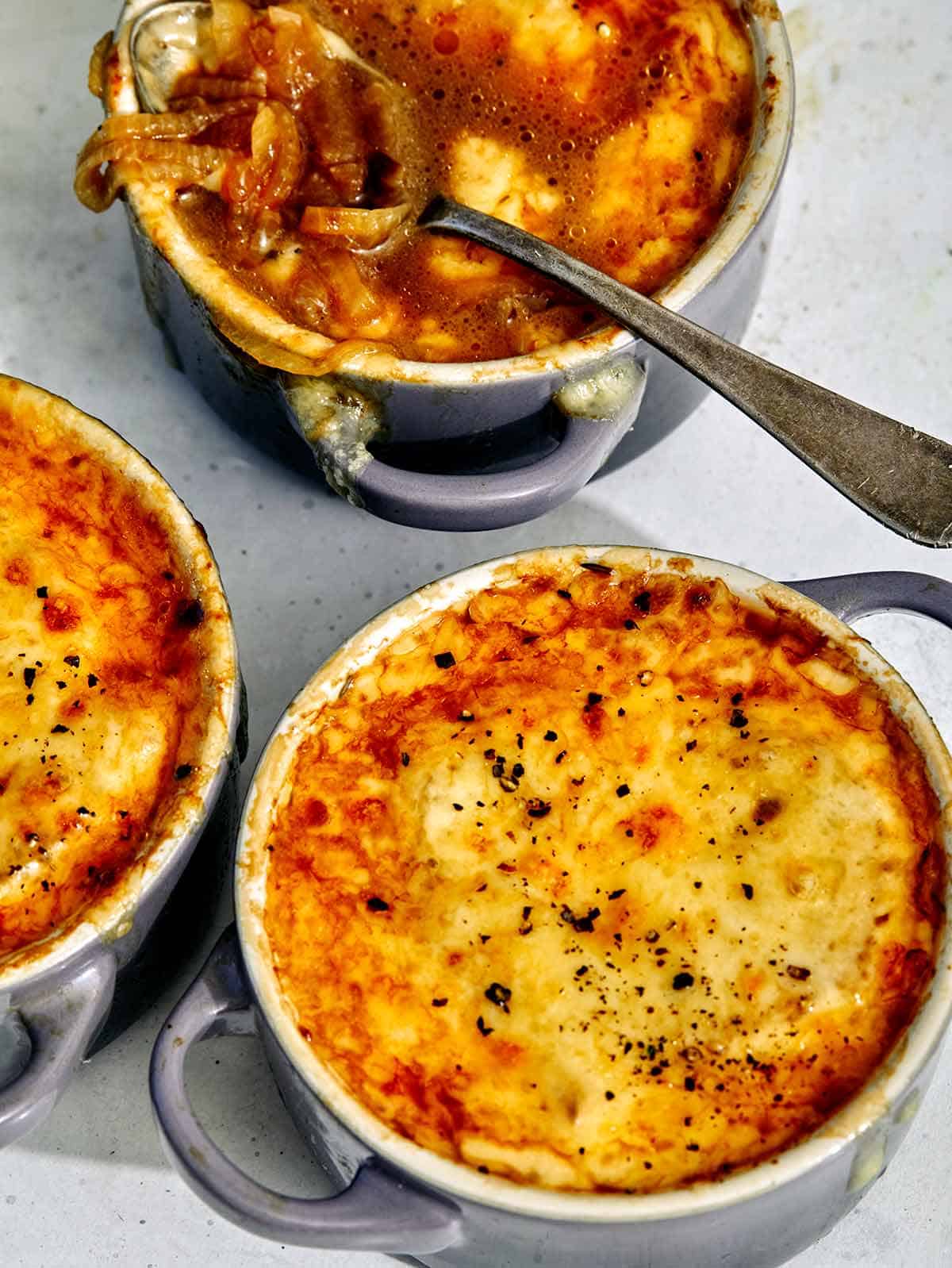 French onion soup in bowls being eaten. 