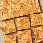 Marbled pumpkin cheesecake bars on a board.