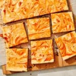 Marbled pumpkin cheesecake bars on a board.