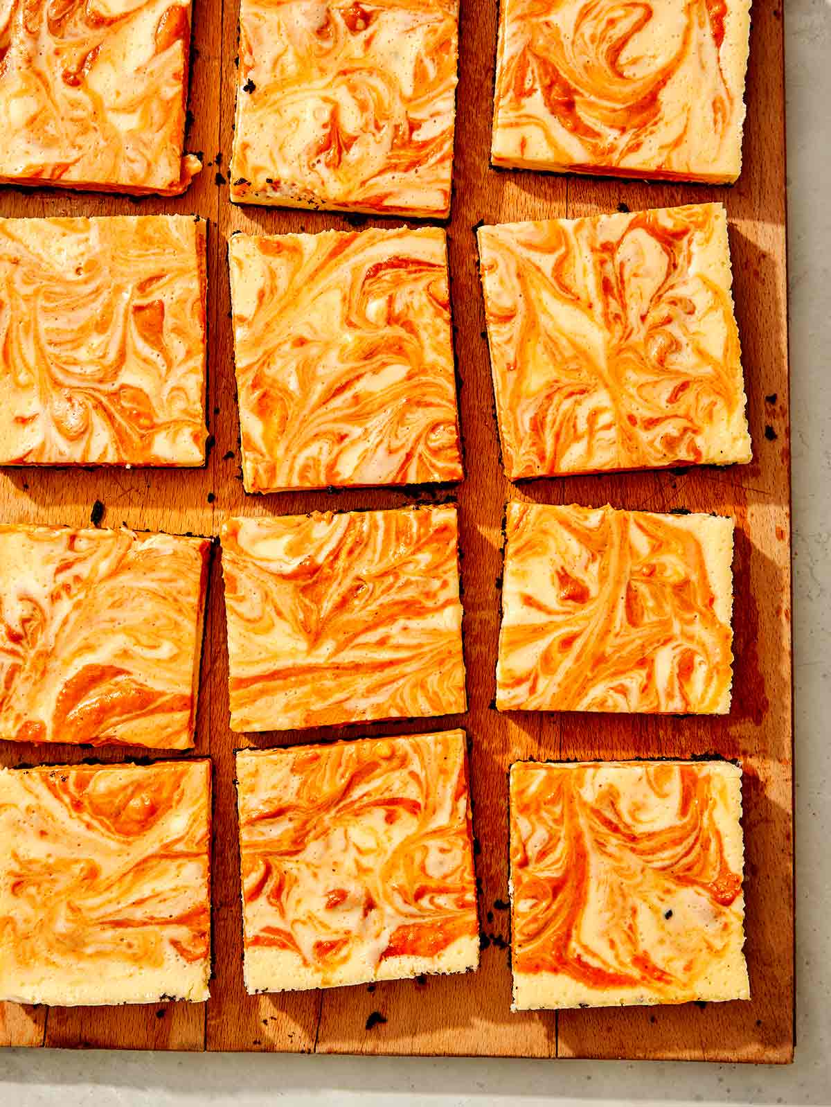 Pumpkin cheesecake bars cut on a board. 