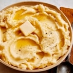 Mashed potatoes in a bowl with a spoon on the side.