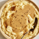 Mashed potatoes with gravy poured over them.