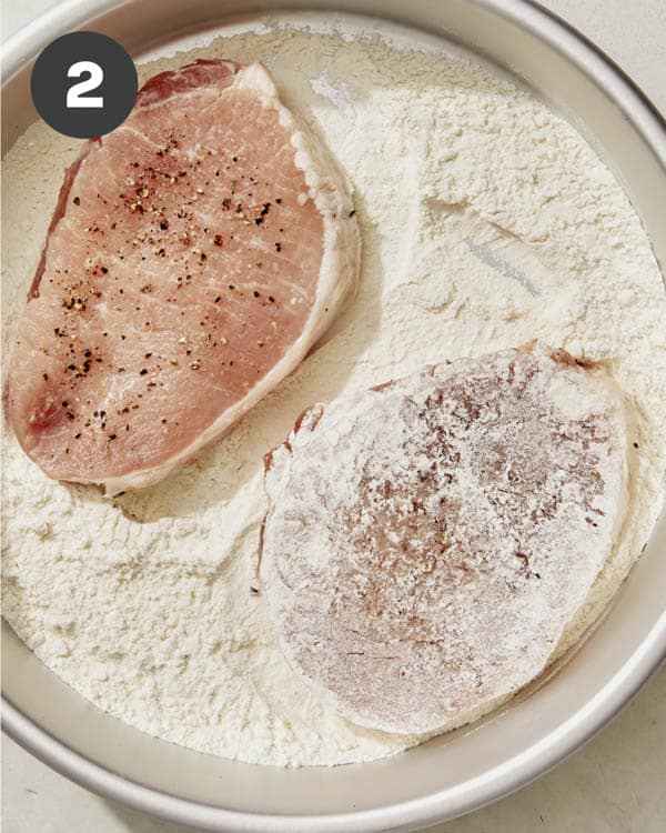 Seasoned pork chops being dredged in flour to make pork katsu sandwiches.