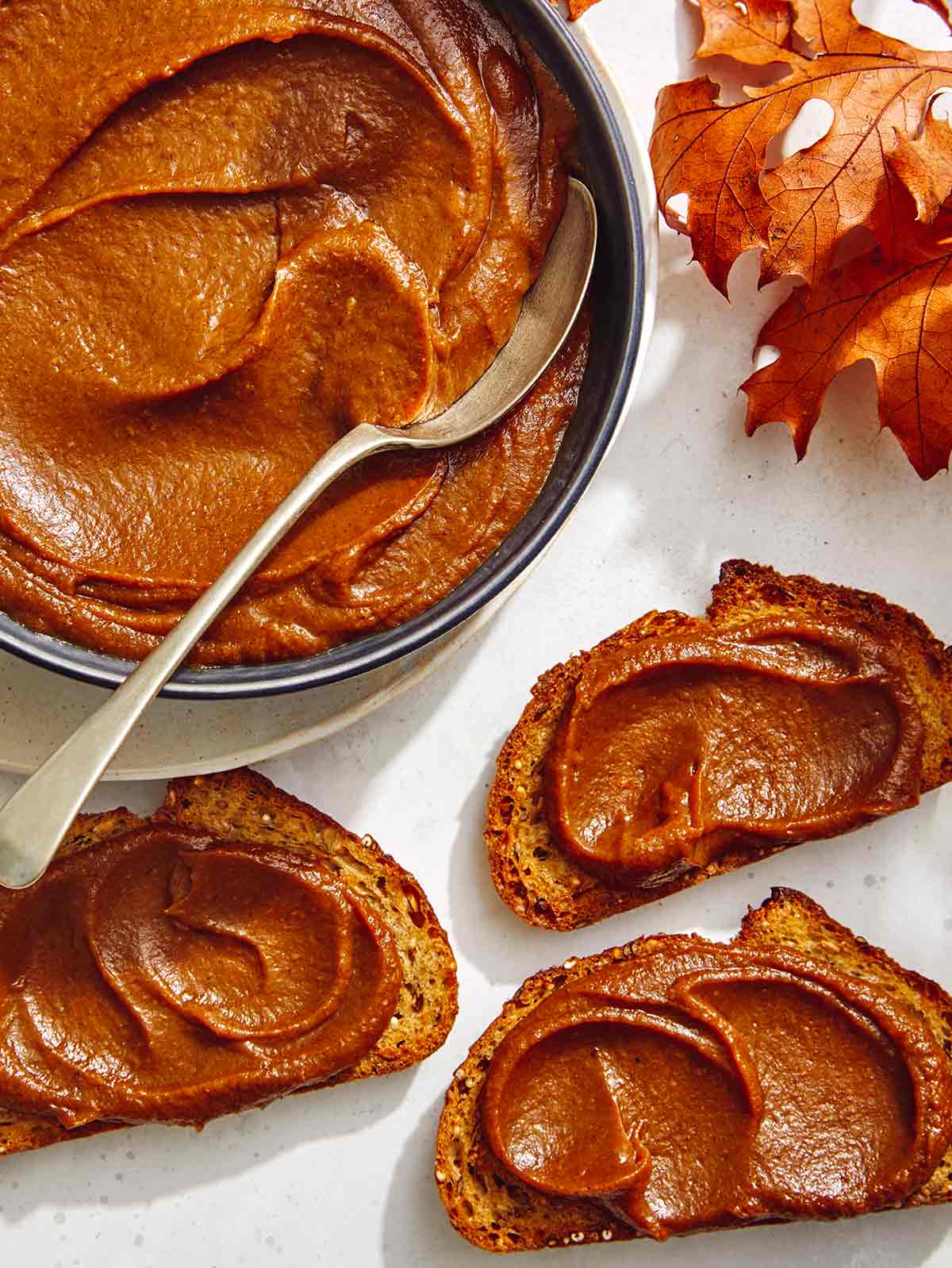 Pumpkin butter in a bowl with a spoon in it. 