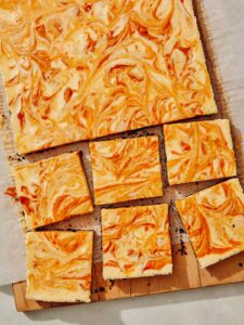 Pumpkin cheesecake bars on a board.