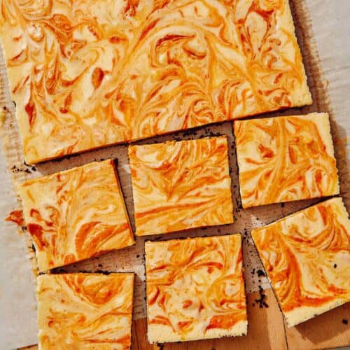 Pumpkin cheesecake bars on a board.