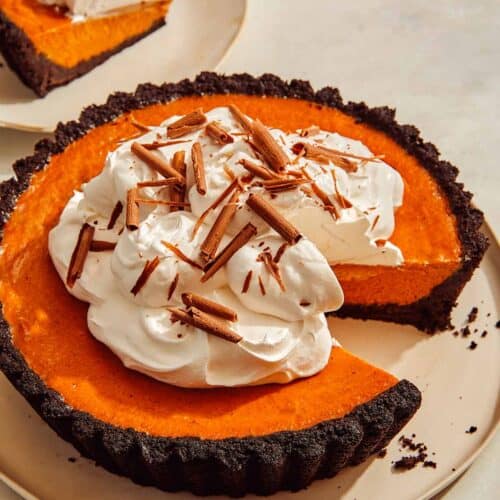 Pumpkin pie with a chocolate crust with a slice taken out.