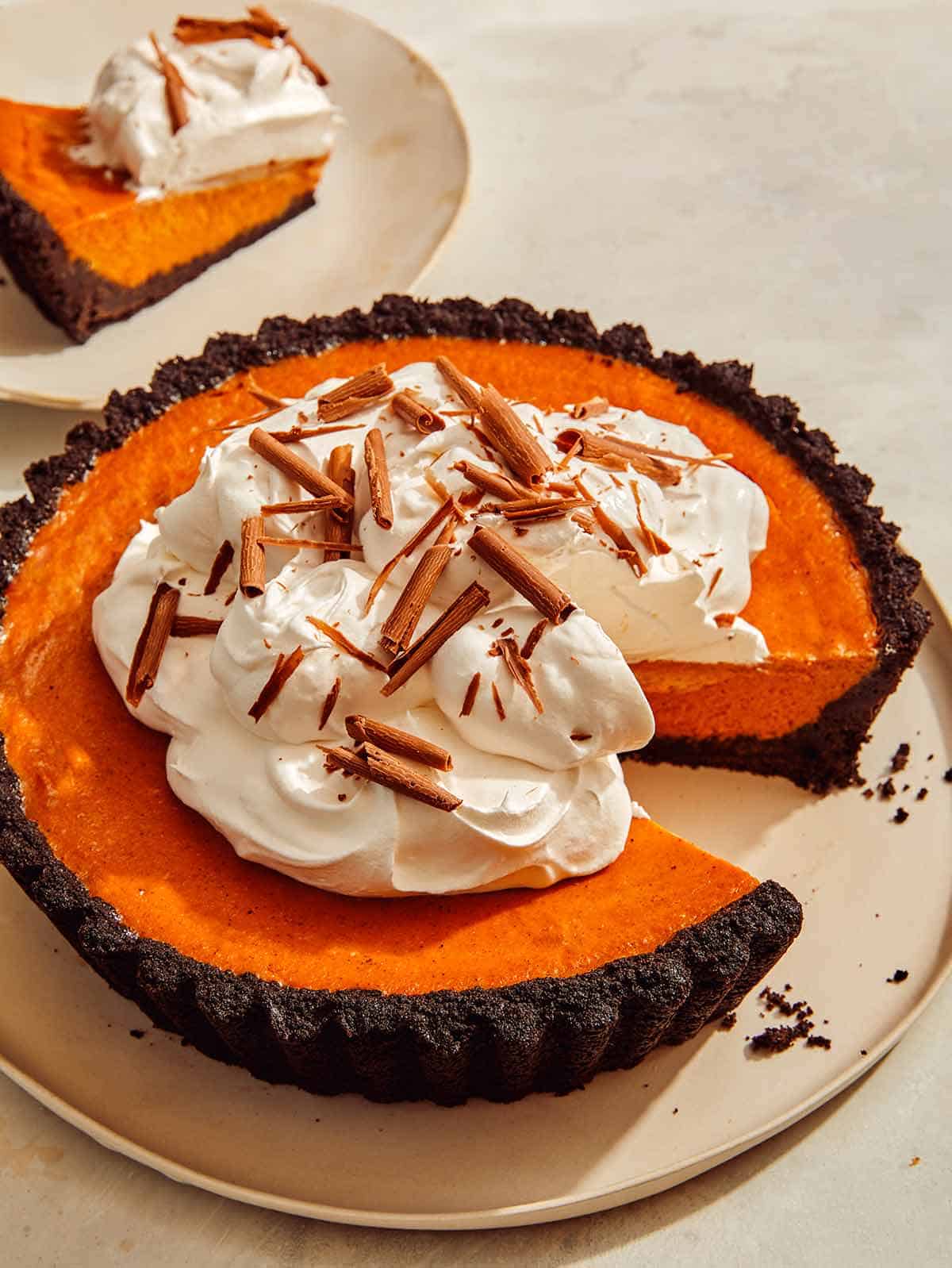 Pumpkin pie with a chocolate crust with a slice taken out. 