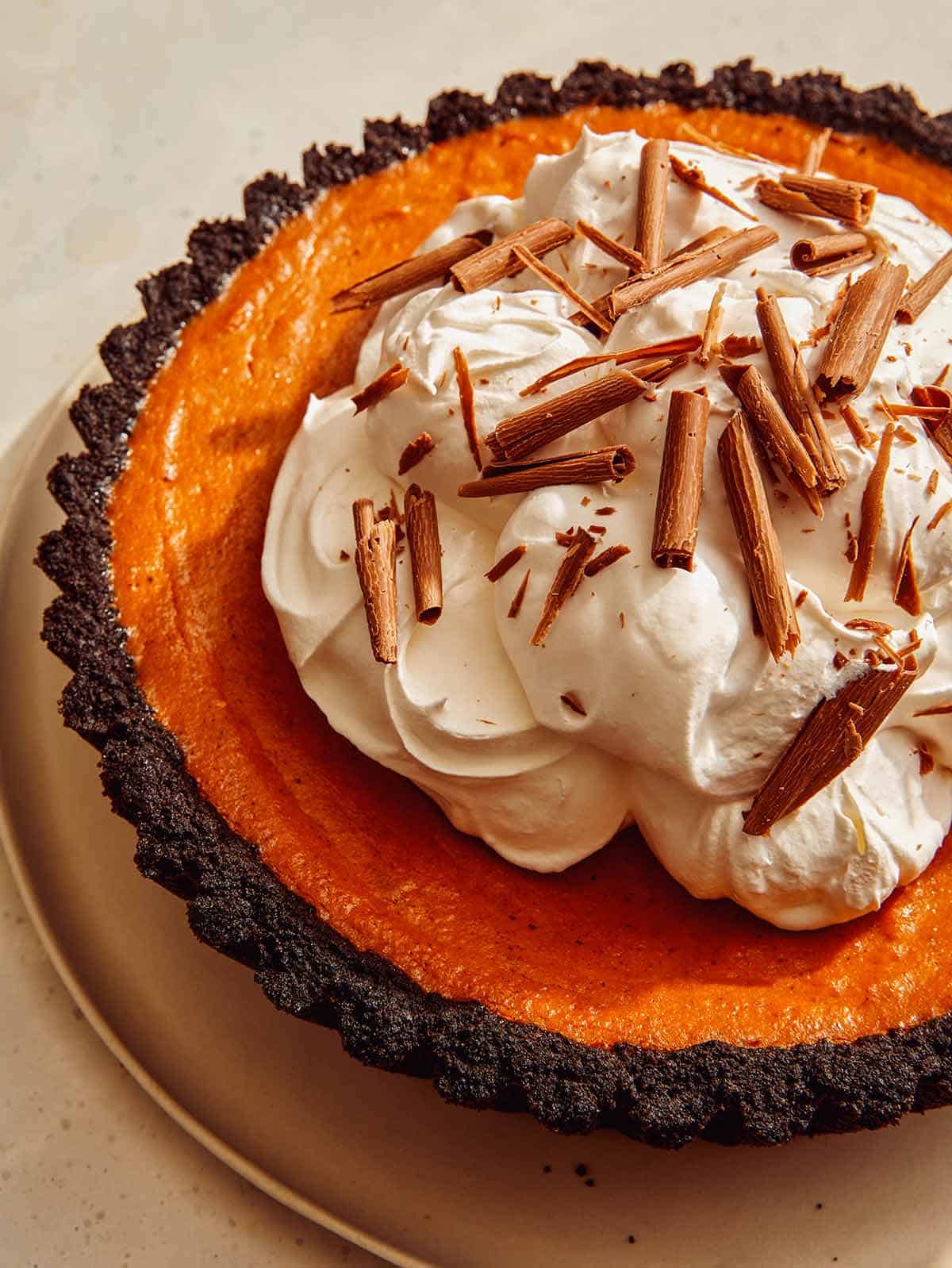 Pumpkin pie with a chocolate crust piled with whipped cream. 