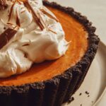 Pumpkin pie with a chocolate crust piled with whipped cream.