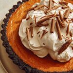 Pumpkin pie with a chocolate crust piled with whipped cream.