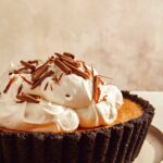 Pumpkin pie with a chocolate crust piled with whipped cream.