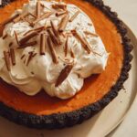 Pumpkin pie with a chocolate crust piled with whipped cream.