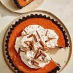Pumpkin pie with a chocolate crust with a slice taken out.
