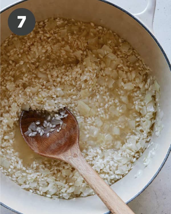 Making risotto with stock and rice in a pot.