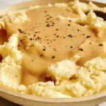 Roasted garlic gravy recipe poured over mashed potatoes.